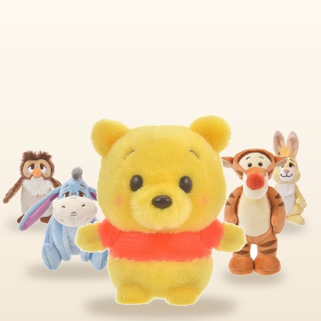 Three soft plush toys in cream, pink and yellow on a light knitted blanket